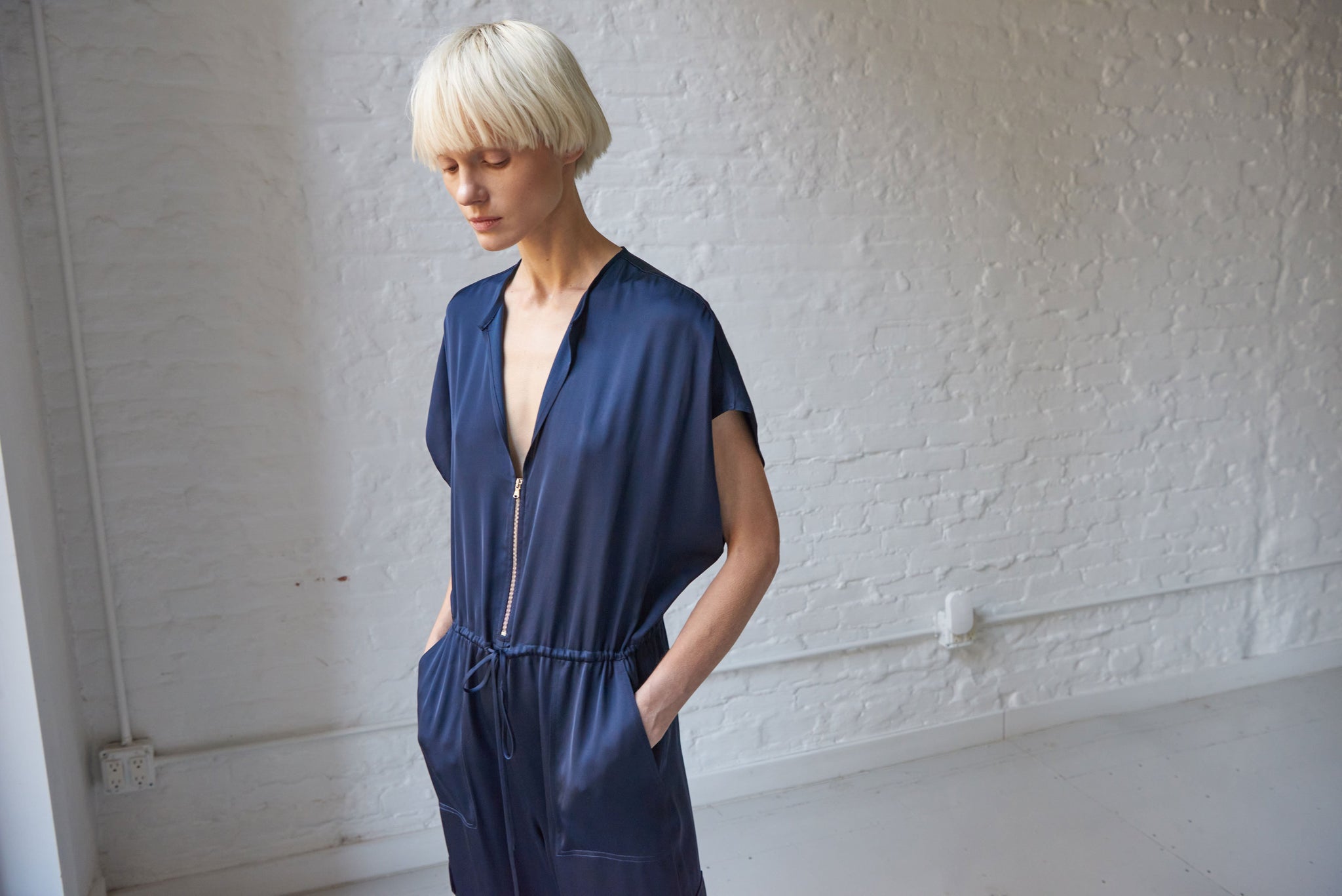 Model wearing navy satin jumpsuit with pockets