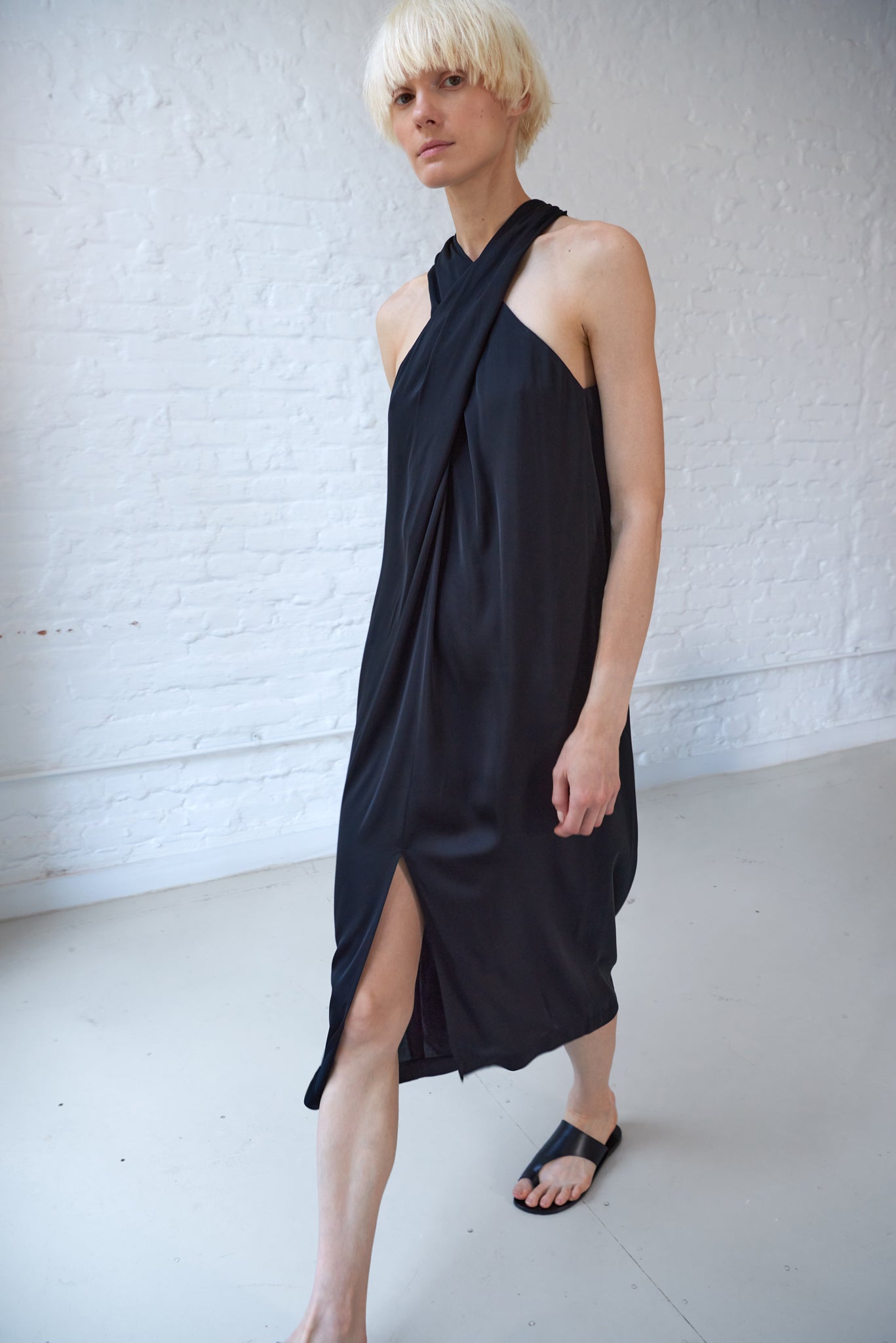 woman looks elegant wearing black halter neck dress made from sustainable viscose satin
