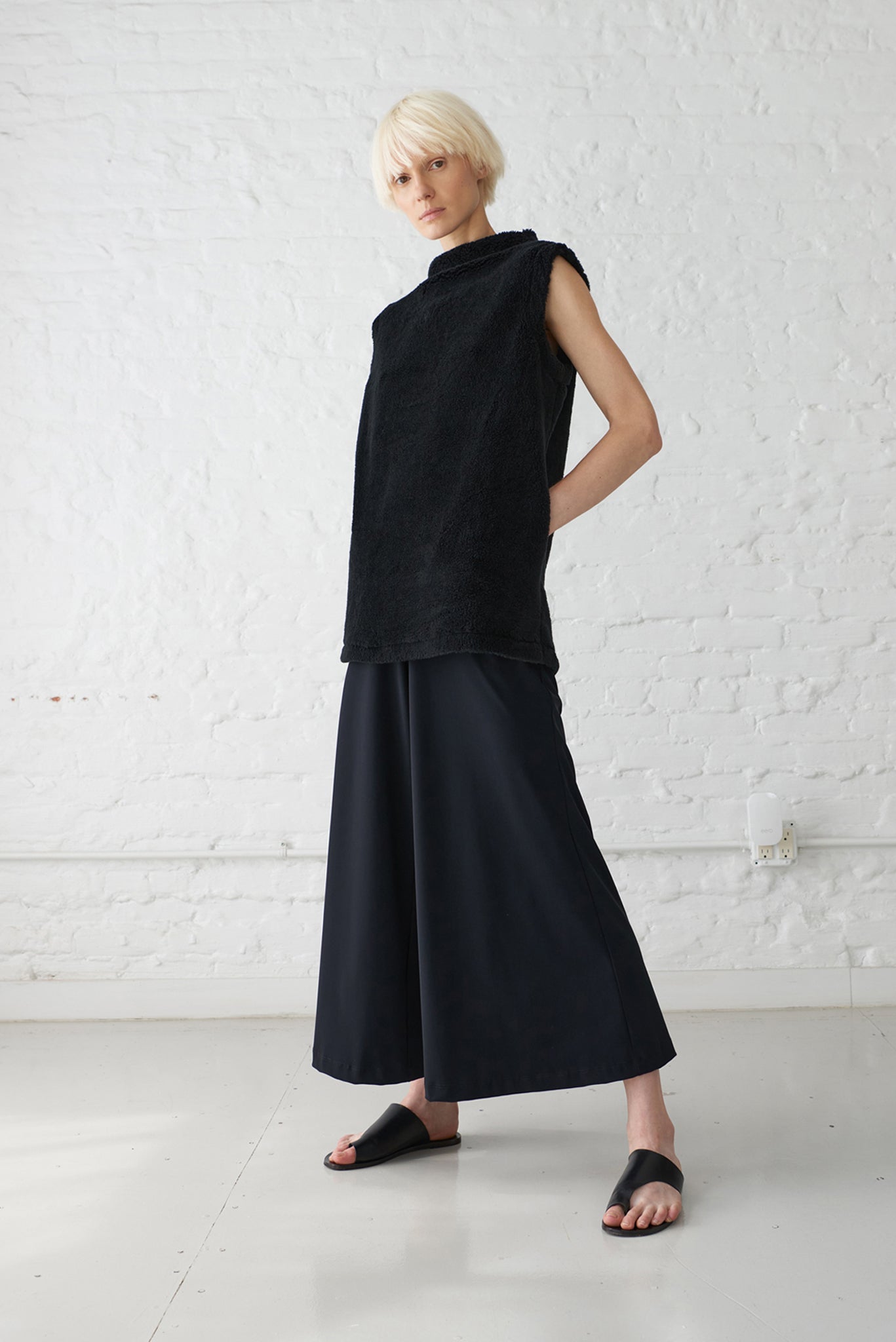 woman wearing pullover vest made with organic cotton yarn in black and wide leg palazzo pants