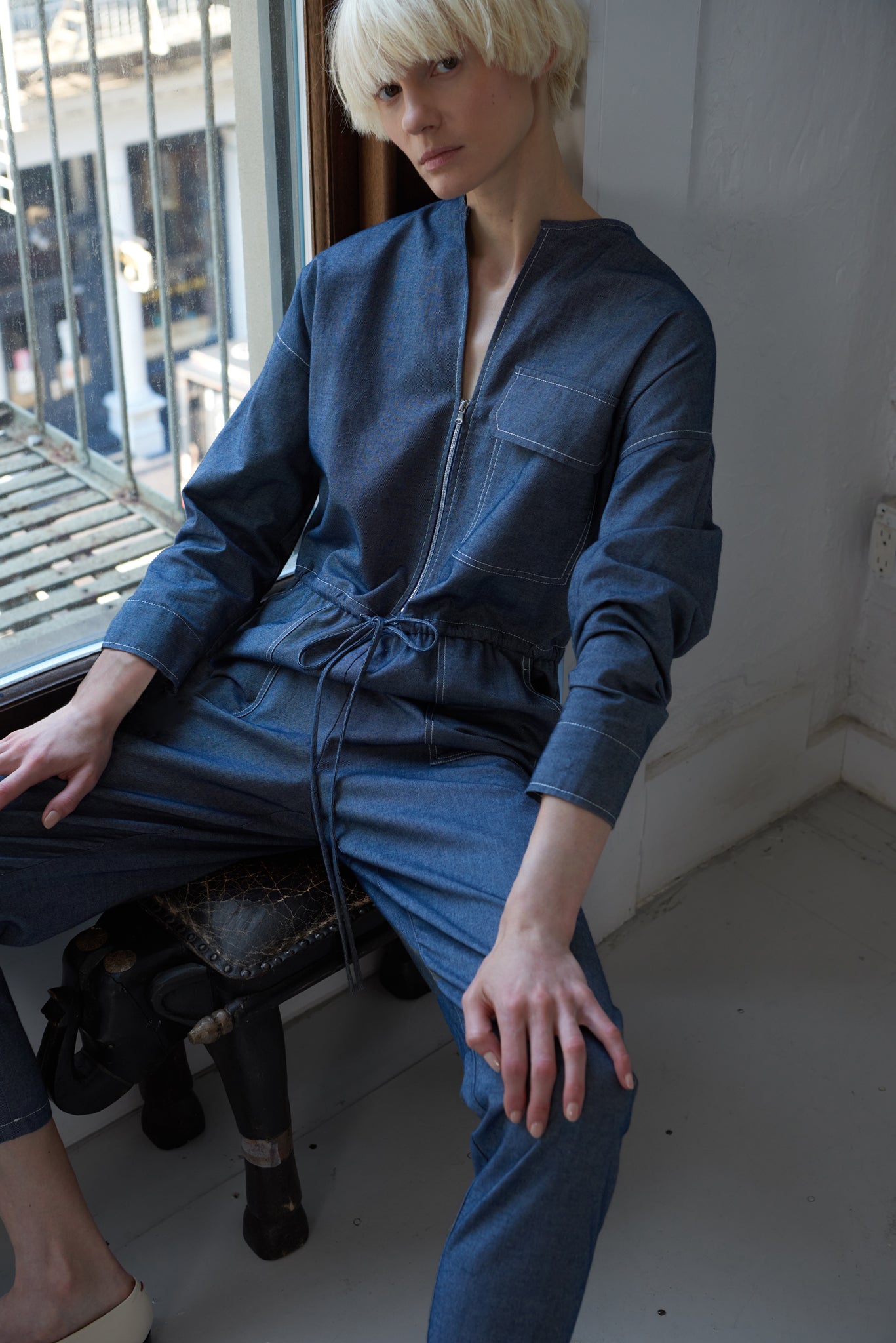 woman sitting wearing japanese denim jumpsuit with sleeves made from GOTS organic cotton in indigo blue