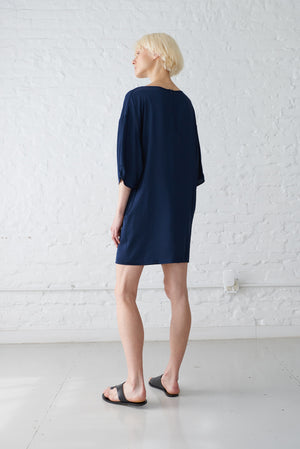 woman wearing kimono sleeve dress made from sustainable viscose fabric in navy blue back view