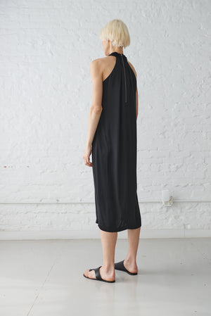 woman wearing black halter neck dress made from sustainable viscose satin back view