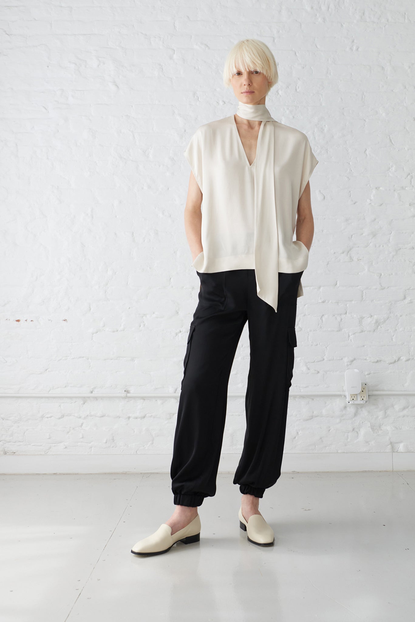 woman wearing tie neck blouse made with a luminous polished viscose satin in ivory