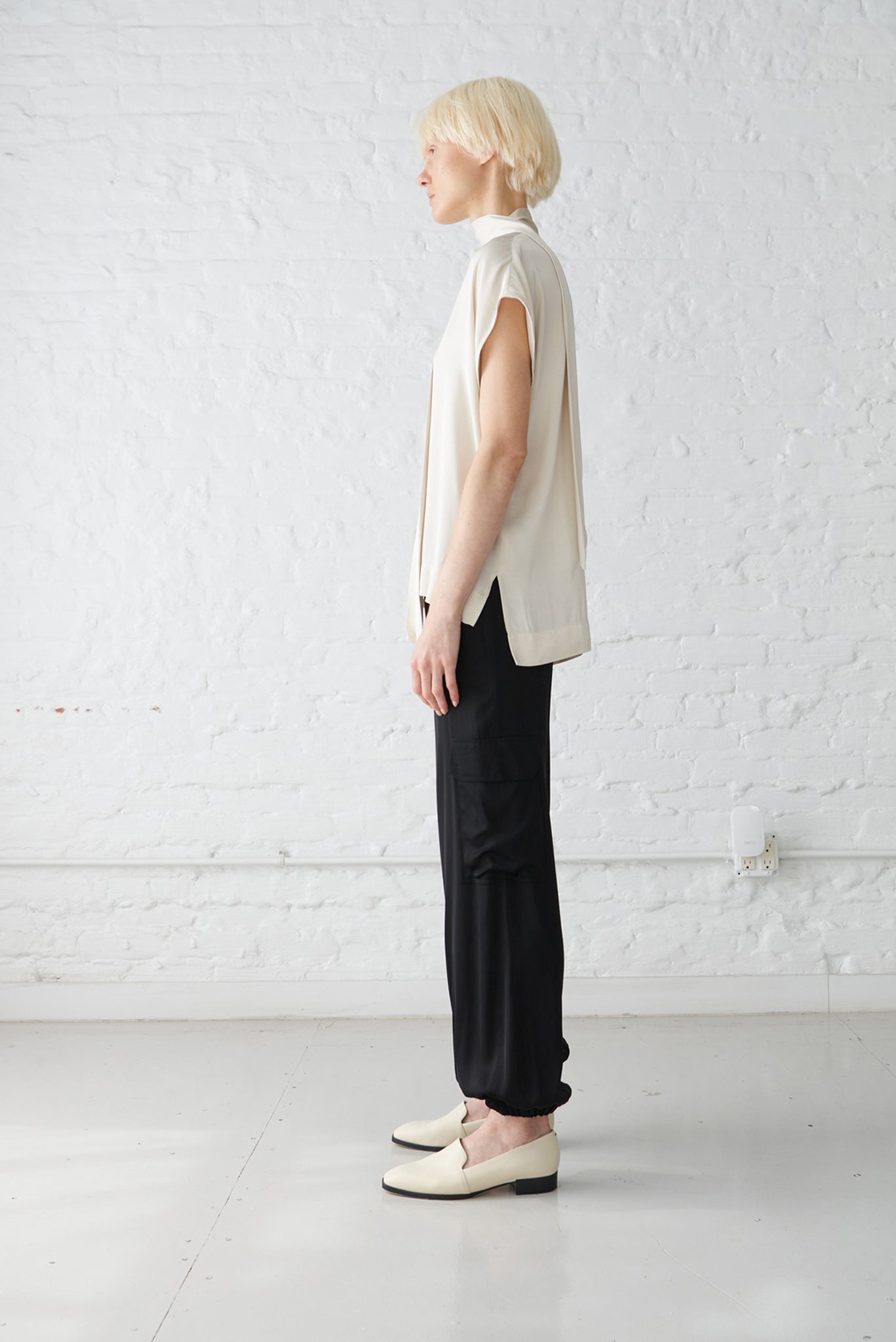 woman wearing tie neck blouse made with a luminous polished viscose satin in ivory and black jogger pants