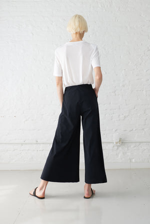 woman wearing wide leg cropped palazzo pants made with Italian recycled jersey in black. Back view.
