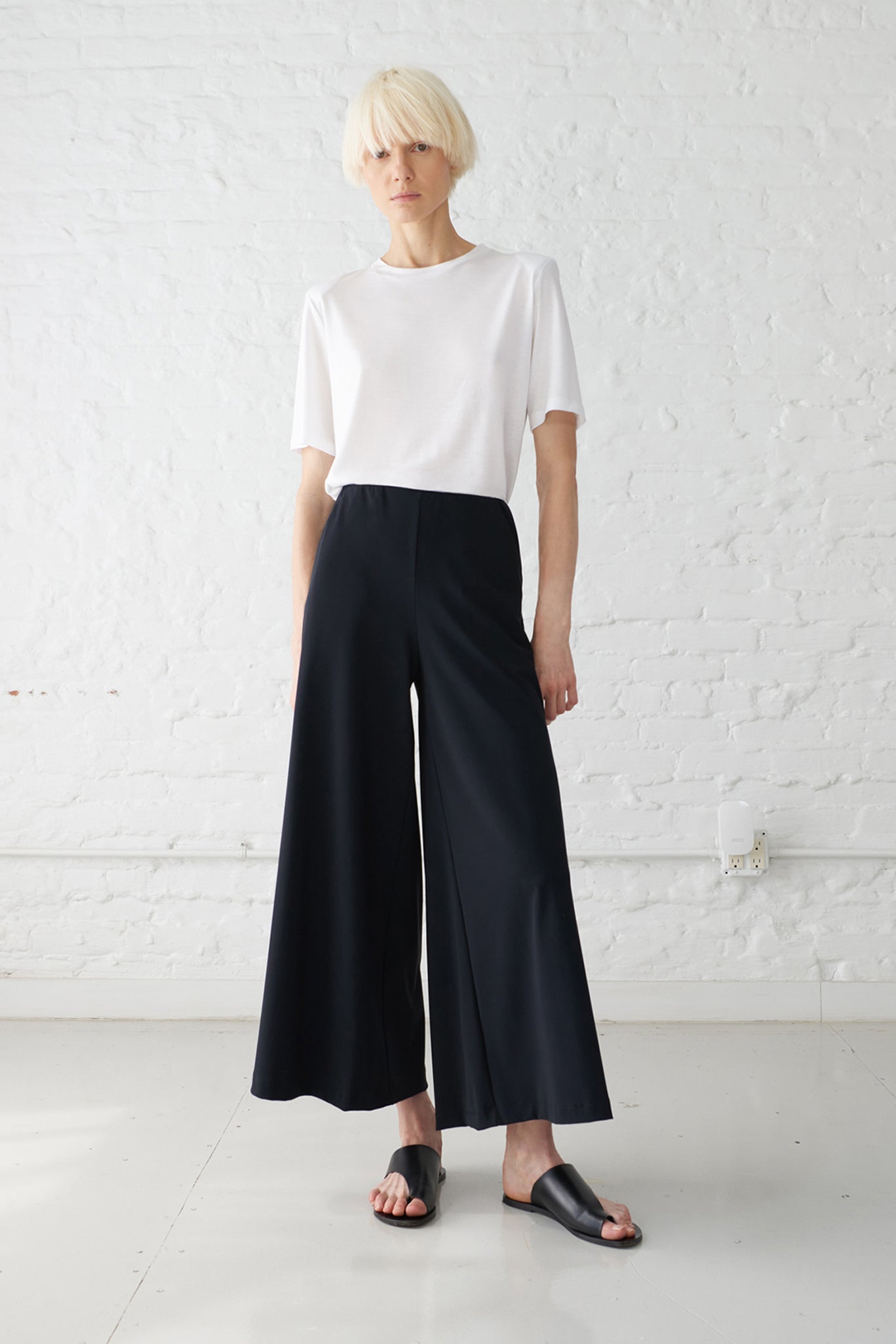 woman wearing wide leg cropped palazzo pants made with Italian recycled jersey in black with white tshirt